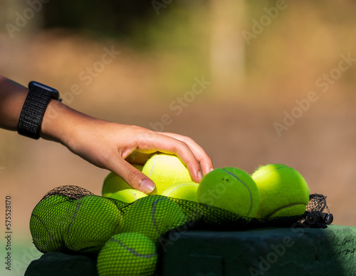 Mano de mujer recogiendo pelota de tenis para comenzar el patirdo
