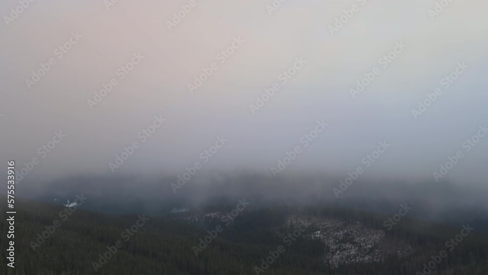 Aerial reveal shot of vibrant sunrise over white dense fog with distant dark peaks of Carpathian mountains on horizon Aerial reveal shot of vibrant sunrise over white dense fog with distant dark peaks of Carpathian mountains on horizon