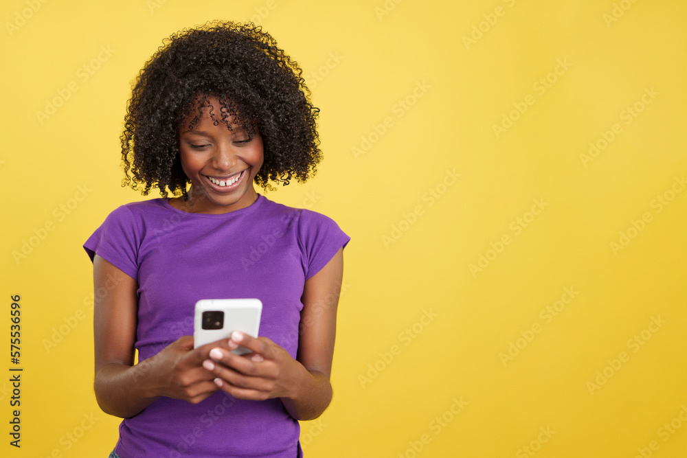 Afro woman smiling while sending a message with a mobile Afro woman smiling while sending a message with a mobile