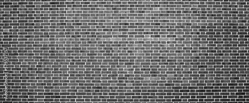 Grayscale backdrop with old realistic black brick wall. Minimal fragment of brickwall close-up. Minimalist monochrome background with wall of gray bricks in different shades. Simple wall texture.