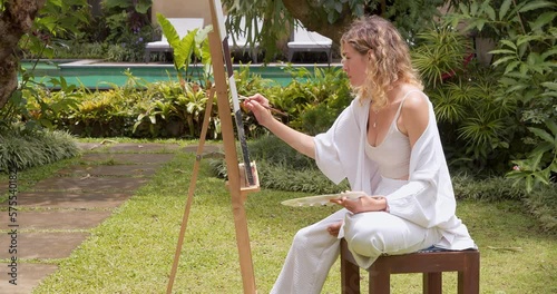 Creative young female artist painting a picture with acrylic paints outdoors. Creativity, hobby and art concept