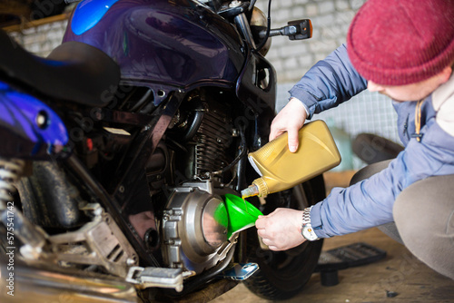 pouring new engine oil into a motorcycle engine.