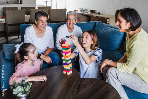 Hispanic family playing Jenga game with grandmother and daughter at home, three generations of women in Mexico Latin America photo
