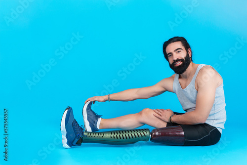 Sportive man with prosthetic leg looking at camera while stretching photo