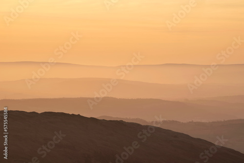 Lovely Winter landscape view from Red Screes across misty layers of mountains towards the East