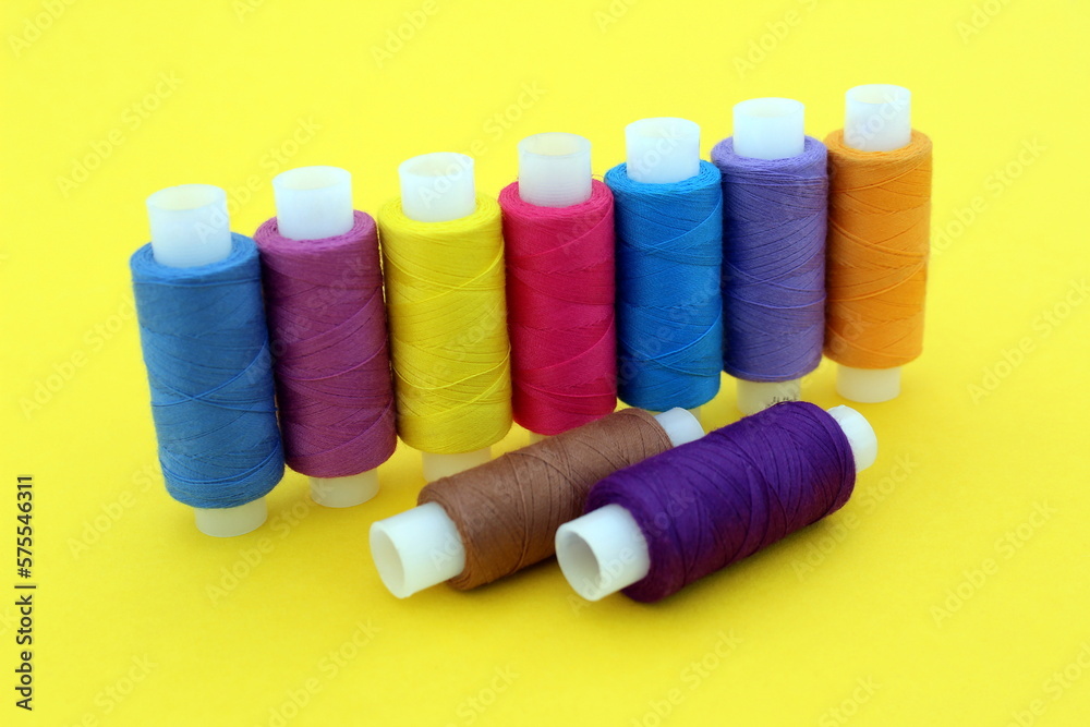 On a yellow background there are many bright multi-colored threads for sewing. On a yellow background there are many bright multi-colored threads for sewing.