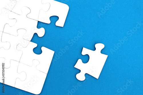 The game, a lot of white puzzle pieces lie on a blue background.