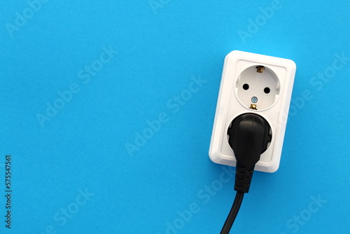 On a blue background is a white double socket with a black plug.