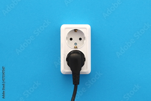 On a blue background is a white double socket with a black plug.