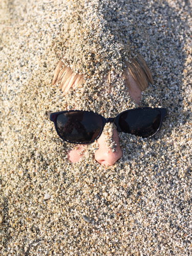 Detail of teen boys face buried in sand photo