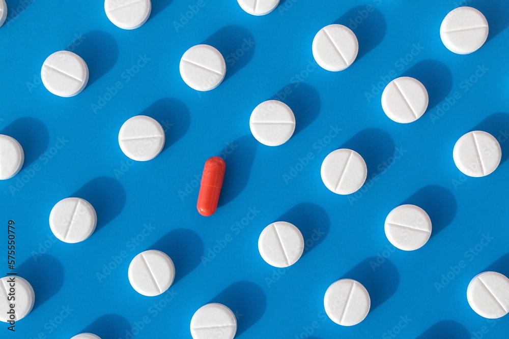 Abstract background of white pills on a blue background with one red capsule.