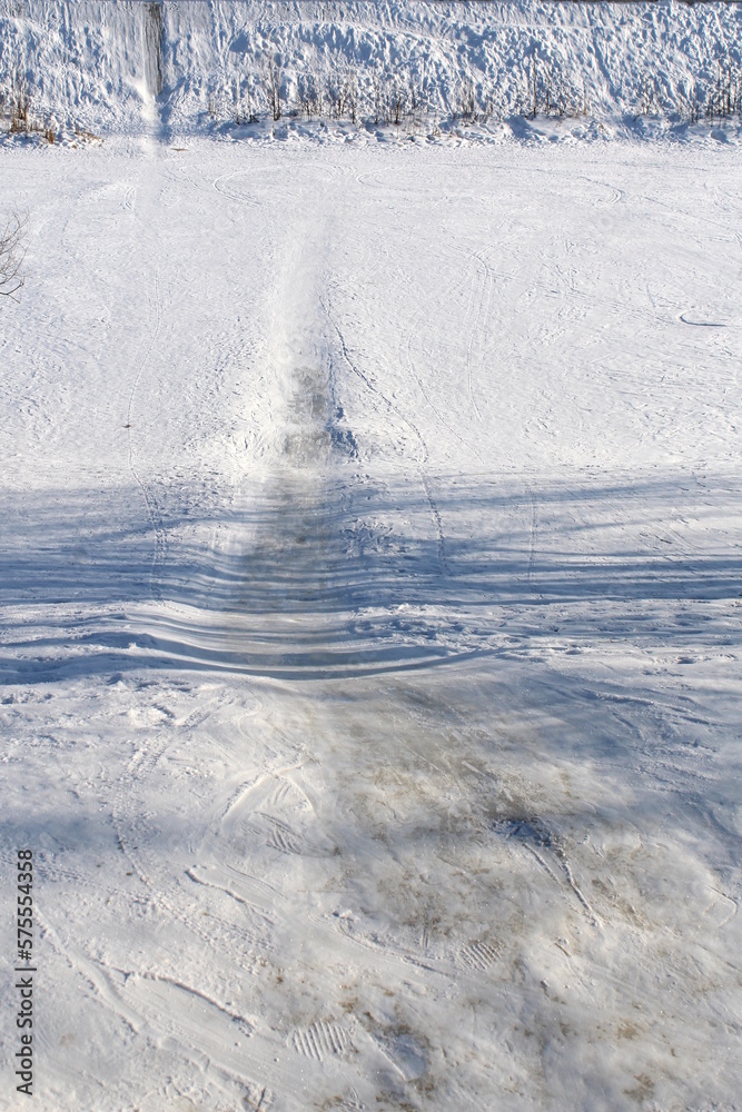 Winter landscape on a sunny day. On the bank of the river, people rolled up a hill. Winter landscape on a sunny day. On the bank of the river, people rolled up a hill.