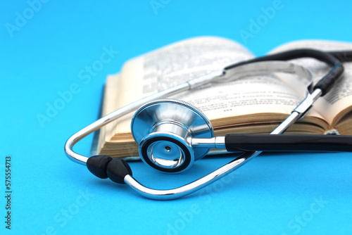 On a blue background lies a textbook with a stethoscope. Medical education theme.