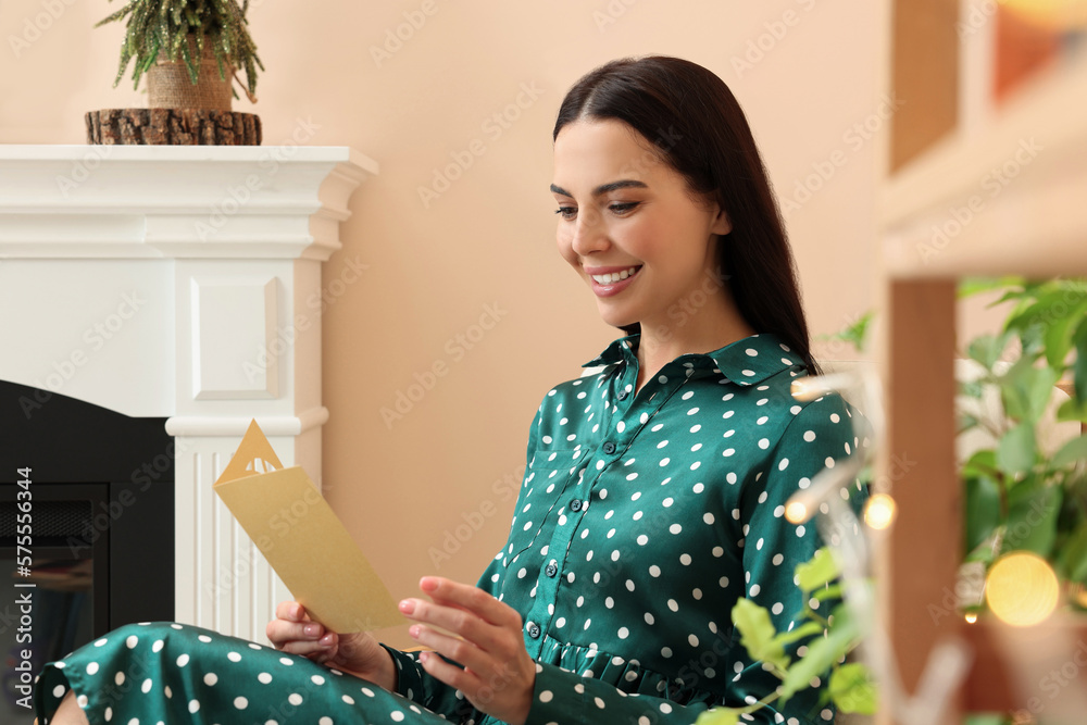 Happy woman reading Christmas greeting card in living room Happy woman reading Christmas greeting card in living room