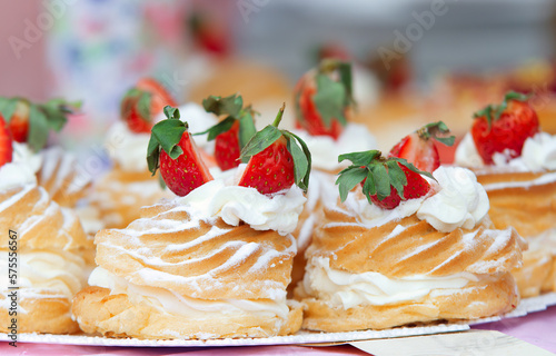 Sale of desserts at farmers street food market in Prague, stand of a local confectioner offering cakes and other desserts. Closeup of wreaths with yolk cream, whipped cream and fresh strawberries.