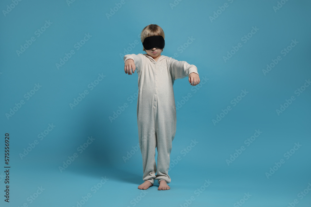 Boy in pajamas and sleep mask sleepwalking on light blue background Boy in pajamas and sleep mask sleepwalking on light blue background