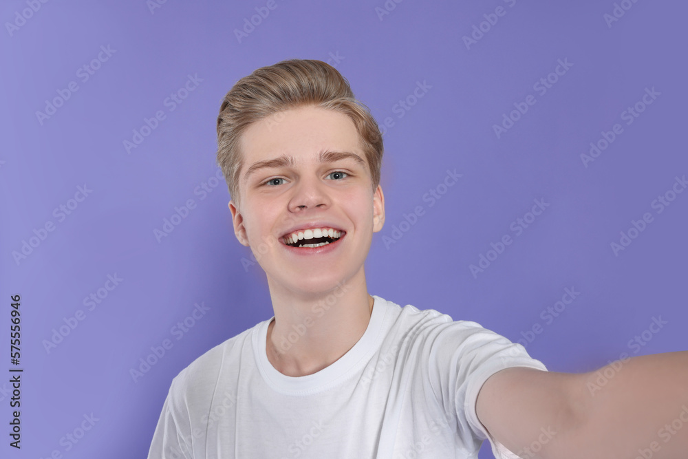 Teenage boy taking selfie on purple background Teenage boy taking selfie on purple background