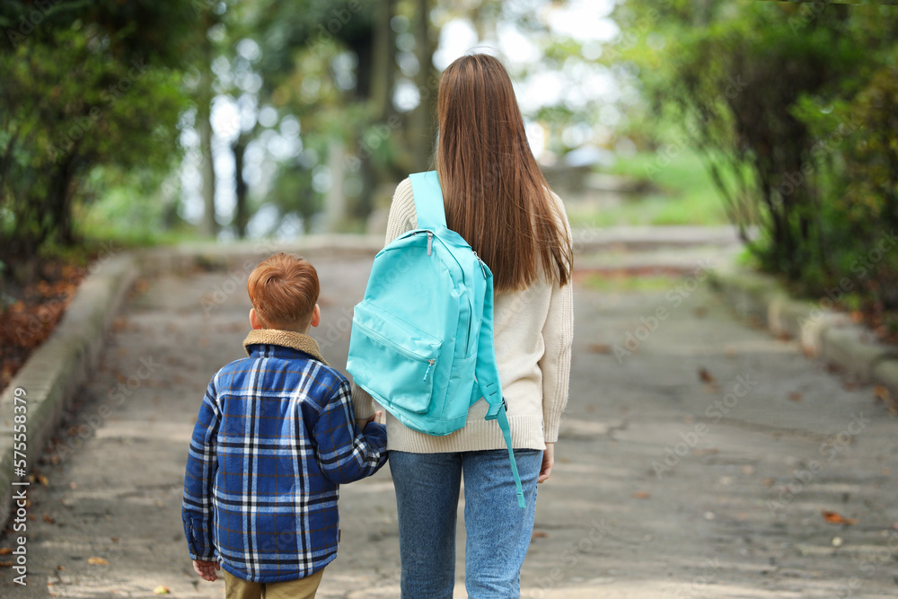 Young mom taking her son to school, back view Young mom taking her son to school, back view