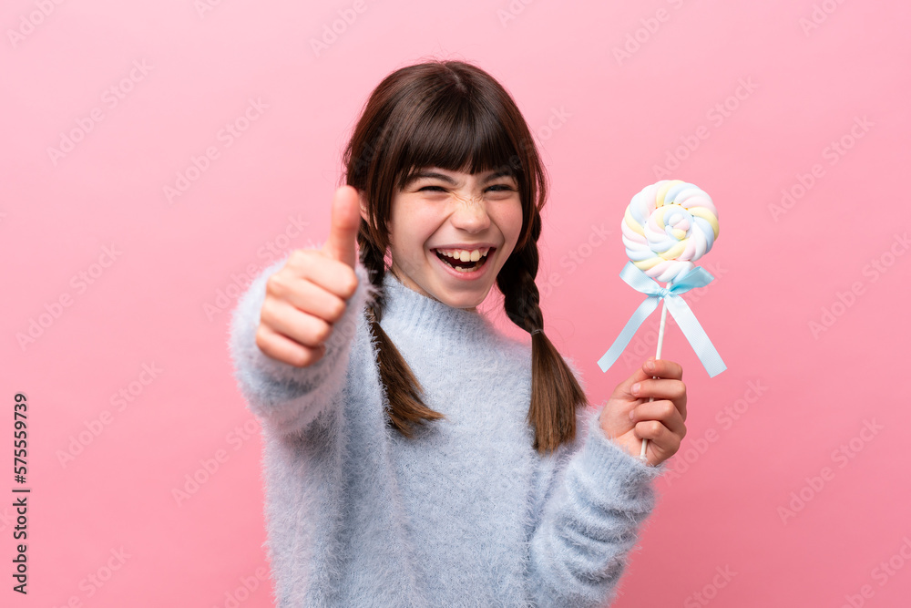 Little caucasian girl holding a lollipop with thumbs up because something good has happened Little caucasian girl holding a lollipop with thumbs up because something good has happened