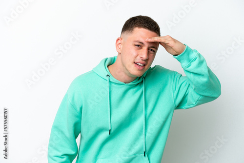 Young brazilian man isolated on white background looking far away with hand to look something © luismolinero
