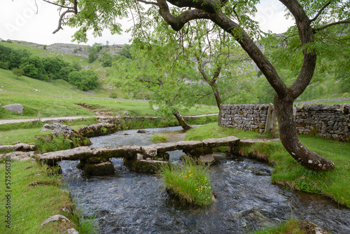 Ancient clapper bridge over the Malham Beck just below Malham Cove, Yorkshire Dales National Park, North Yorkshire, UK photo