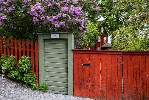 Photography Red wooden fence with gate with flowering lilac trees in Stockholm, Sweden