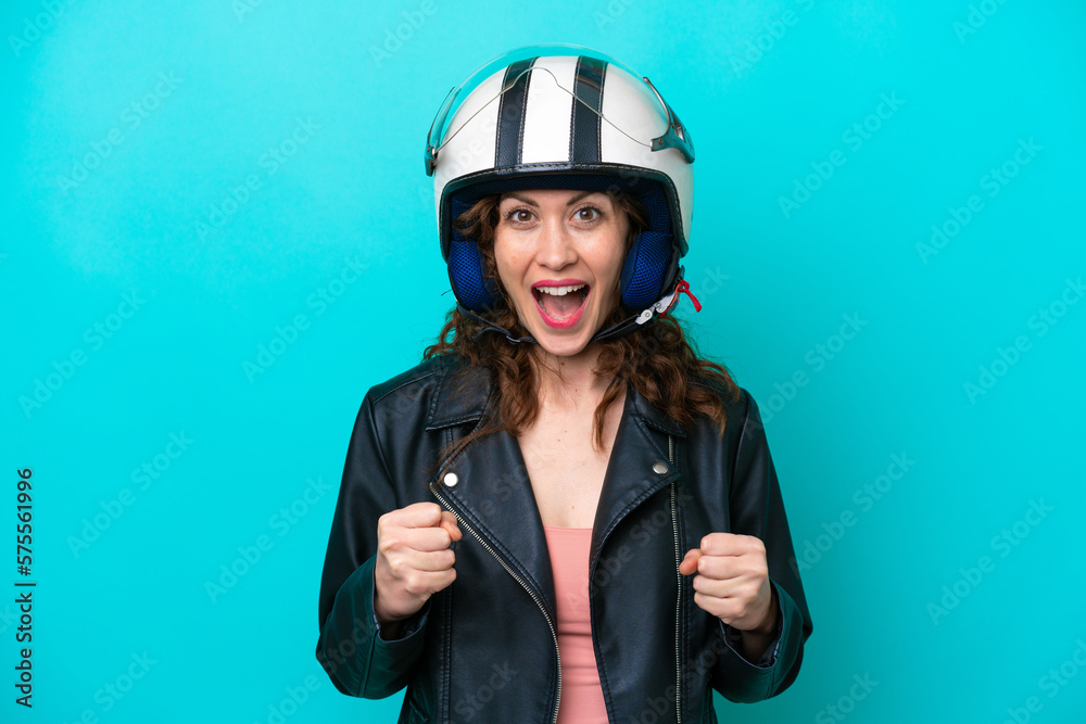 Young caucasian woman with a motorcycle helmet isolated on blue background celebrating a victory in winner position Young caucasian woman with a motorcycle helmet isolated on blue background celebrating a victory in winner position