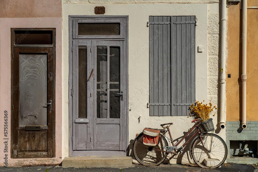 Vintage bicycle with spikelets in the basket parked in front of the old house facade in southern France. Relaxed street atmosphere of the sea village.