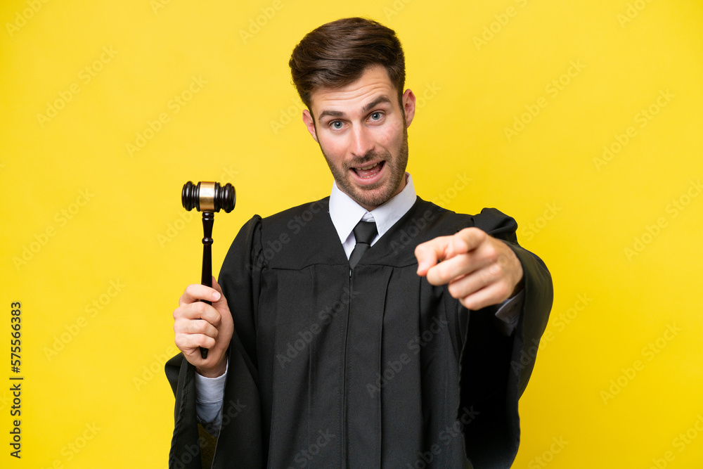 Judge caucasian man isolated on yellow background surprised and pointing front Judge caucasian man isolated on yellow background surprised and pointing front