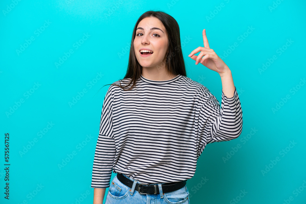 Young caucasian woman isolated on blue background intending to realizes the solution while lifting a finger up Young caucasian woman isolated on blue background intending to realizes the solution while lifting a finger up