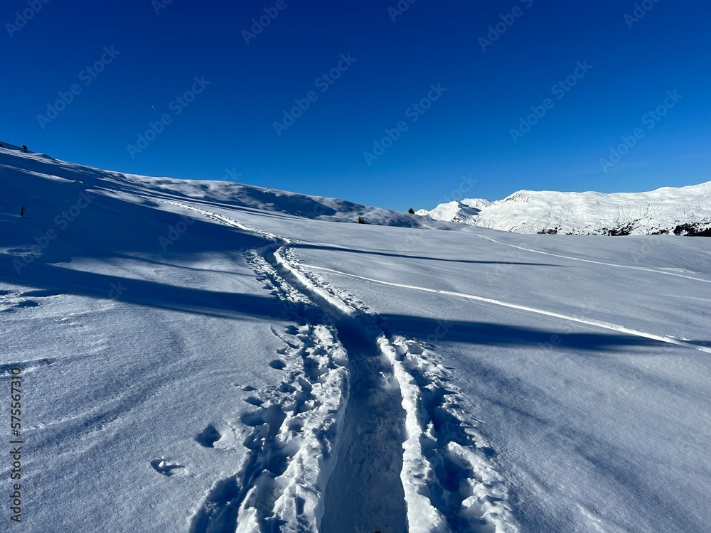 Wonderful winter hiking trails and traces in the fresh alpine snow cover of the Swiss Alps and over the tourist resort of Arosa - Canton of Grisons, Switzerland (Schweiz) Wonderful winter hiking trails and traces in the fresh alpine snow cover of the Swiss Alps and over the tourist resort of Arosa - Canton of Grisons, Switzerland (Schweiz)