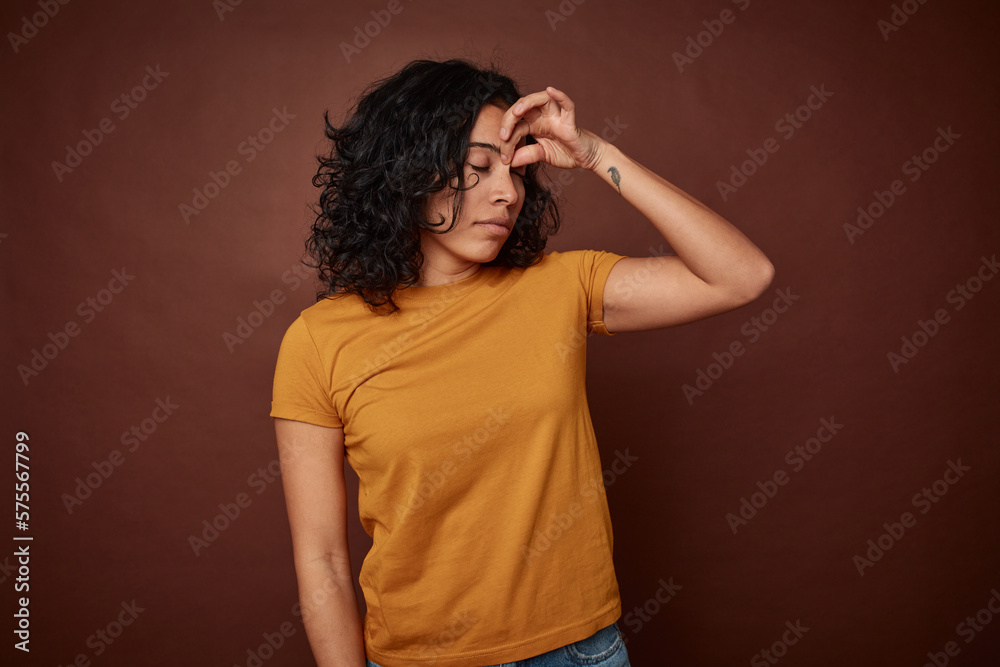 Young colombian curly hair woman isolated on brown background having a head ache, touching front of the face.