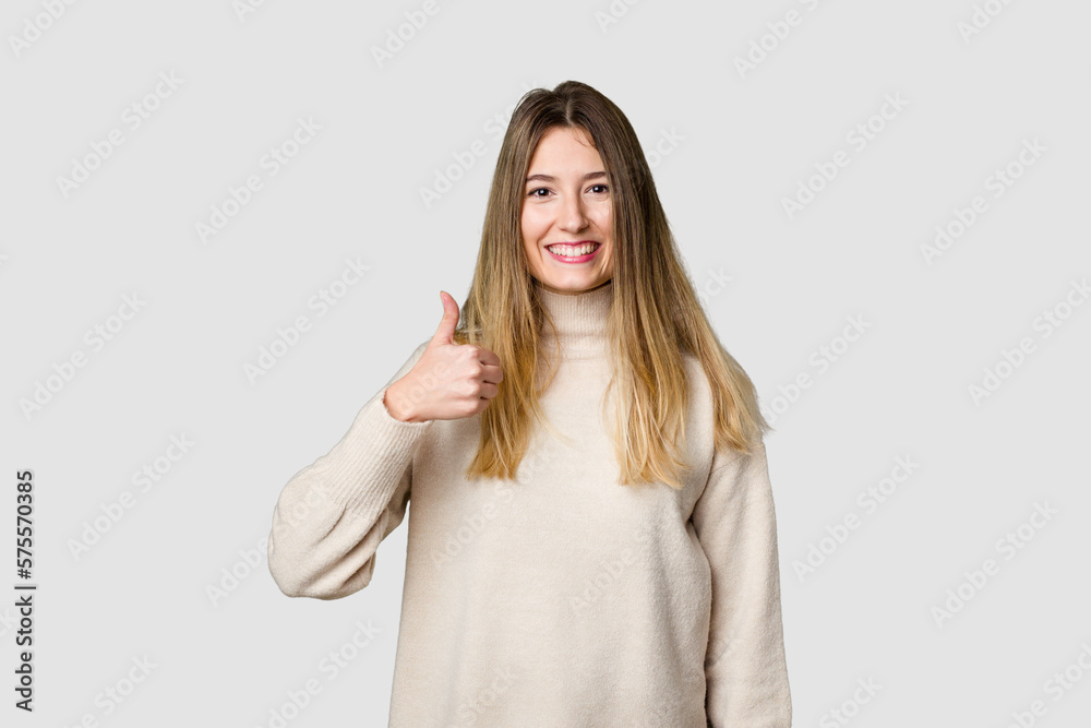 Young blonde posing for a portrait isolated, exuding natural beauty and radiance smiling and raising thumb up Young blonde posing for a portrait isolated, exuding natural beauty and radiance smiling and raising thumb up