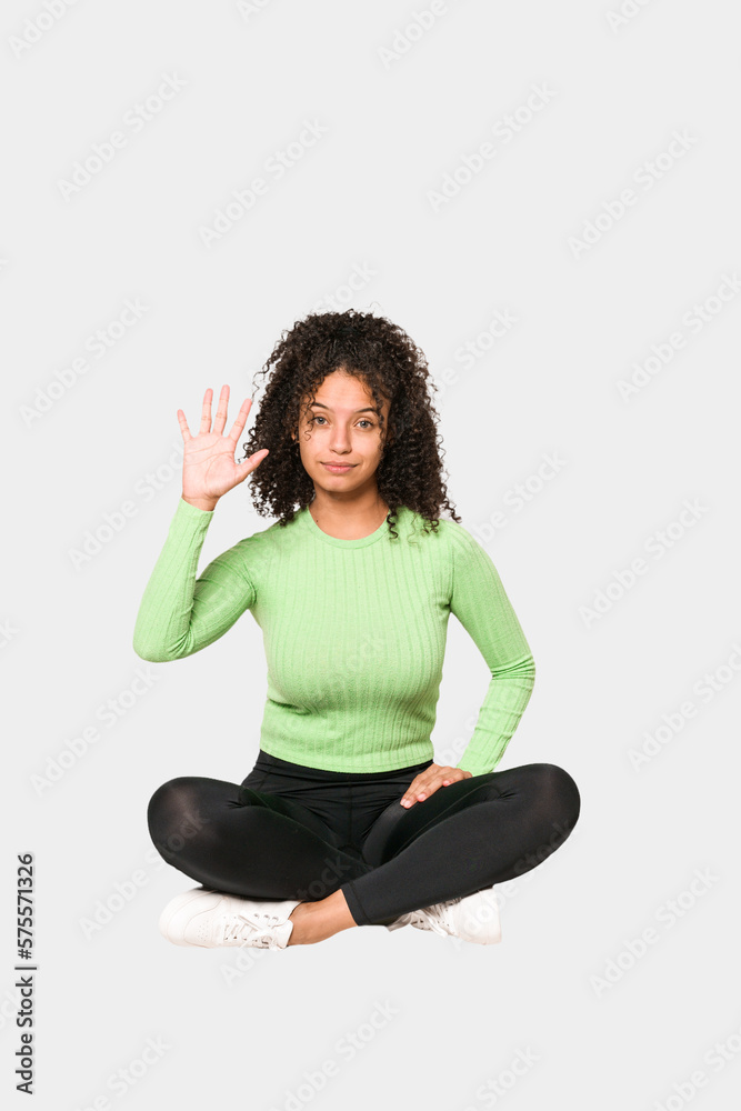 Young african american curly woman sitting on the floor isolated Young african american curly woman sitting on the floor isolated