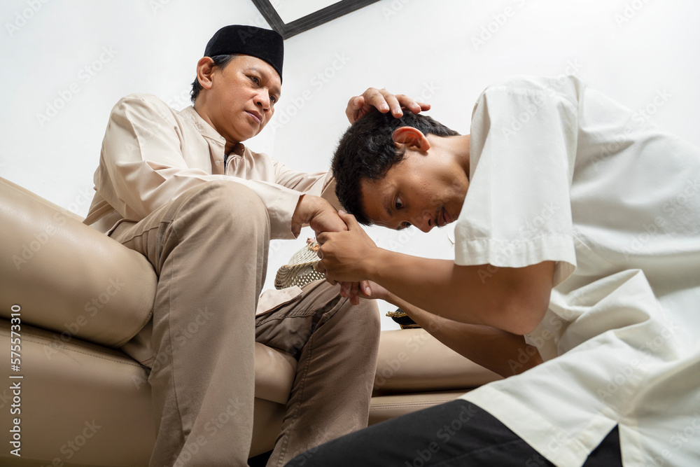 Fototapeta premium Asian Muslim man asking forgiveness from his father