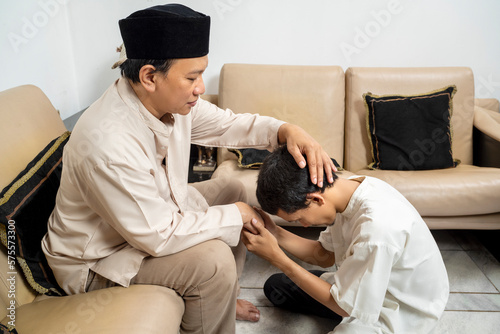 Asian Muslim man asking forgiveness from his father photo