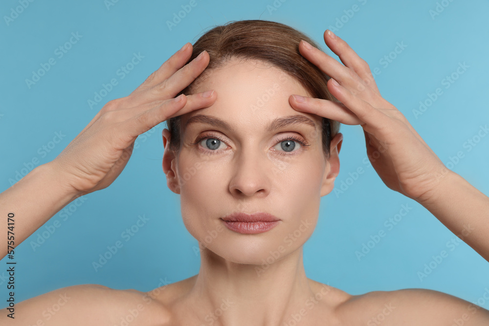 Naklejka premium Woman massaging her face on turquoise background