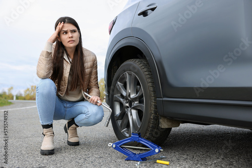 Worried young woman near car with punctured wheel on roadside © New Africa