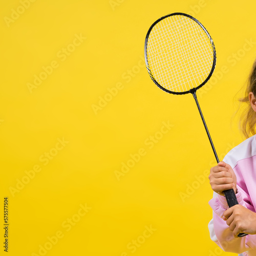 Full length studio photo of ten year old girl holding badminton racket and isolated on yellow. © Ivan Zelenin