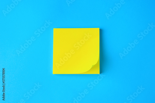 Blank paper note on light blue background, top view