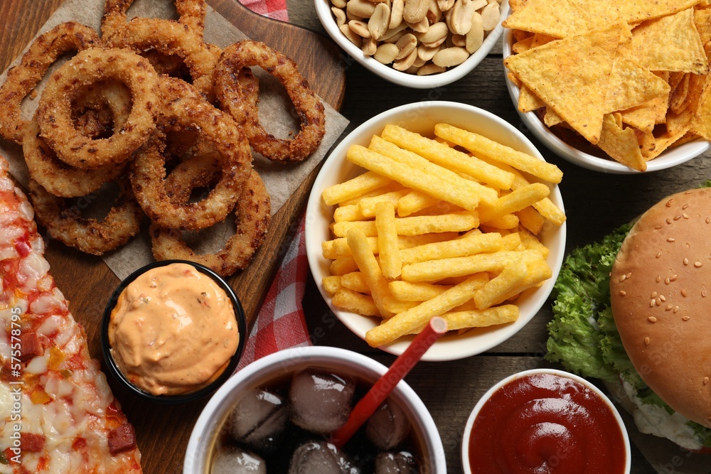 French fries, onion rings and other fast food on wooden table, flat lay