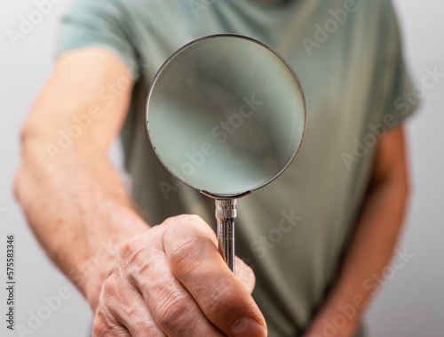 Hand holding magnfier. Looking through magnifying glass lens. Search, find, seek, test concept