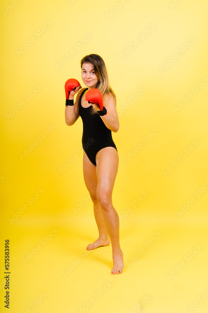 Fototapeta premium Cool female fighter in boxing bandages trains in studio. Mixed martial arts.