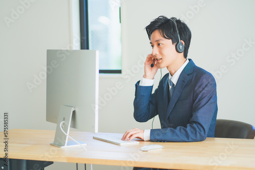 ヘッドセットをつけてインサイドセールスをするスーツ姿の若い男性