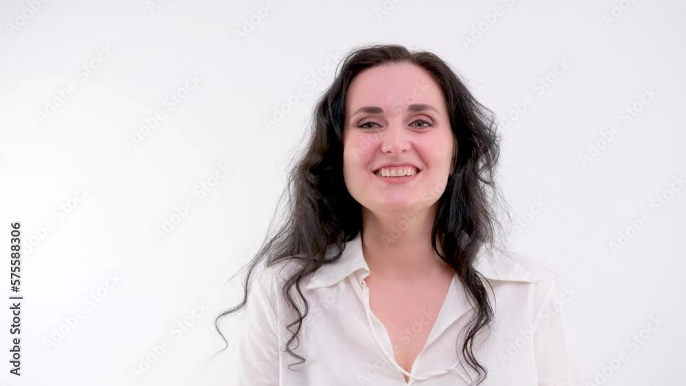 sincere laughter of an adult woman with black hair she shows a finger waving at us smiling on a white background Light clothes clean skin relationship communication emotions joke funny story
