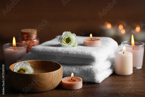 Beautiful spa composition with burning candles and flowers on wooden table