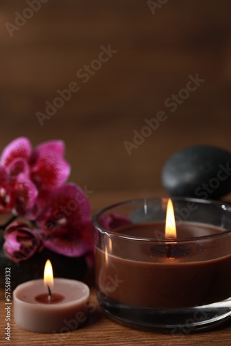 Beautiful spa composition with burning candles and flowers on wooden table