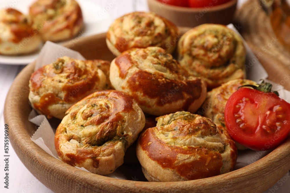 Fresh delicious puff pastry with tasty filling and tomato in wooden bowl, closeup