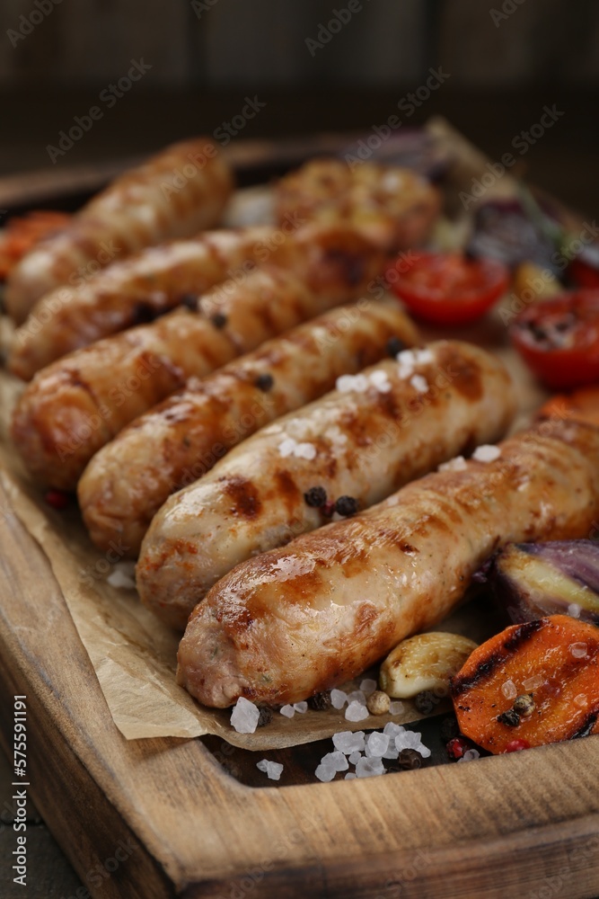 Tasty grilled sausages with vegetables on wooden table, closeup Tasty grilled sausages with vegetables on wooden table, closeup