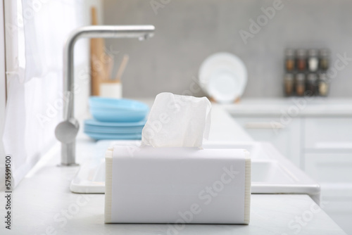 Package of paper towels on white countertop near sink in kitchen